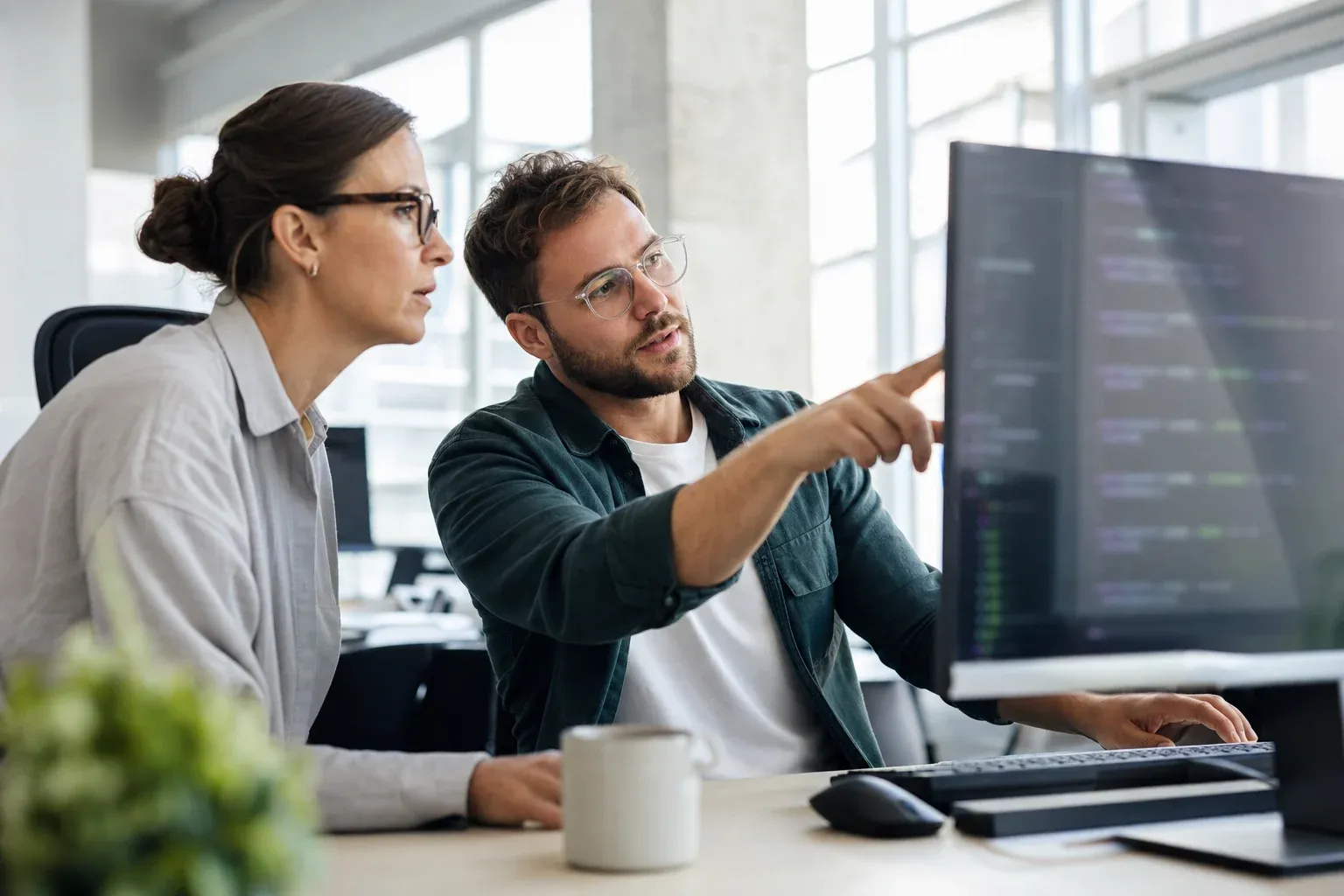 Entwickler modelliert Fachprozesse als Diagramme an zwei Bildschirmen